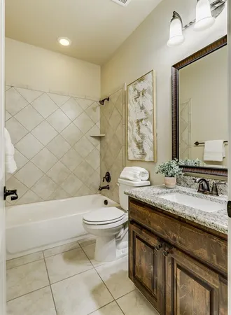a bathroom with a granite countertop sink a toilet a mirror and shower