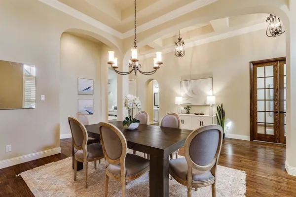 a dining room with wooden floor a chandelier a wooden table and chairs