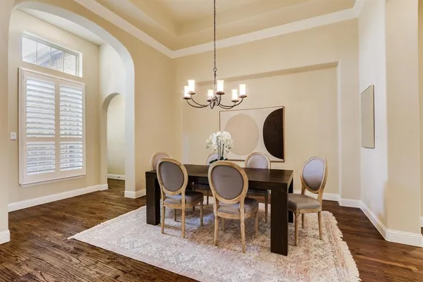 a dining room with chandelier fan and wooden floor
