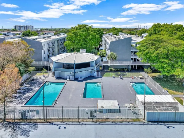 an aerial view of a house with swimming pool and large trees