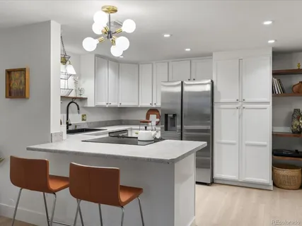 a kitchen with stainless steel appliances granite countertop a sink a stove a refrigerator cabinets and chairs