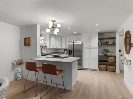 a kitchen with stainless steel appliances a stove a refrigerator a sink dishwasher a dining table and chairs with wooden floor