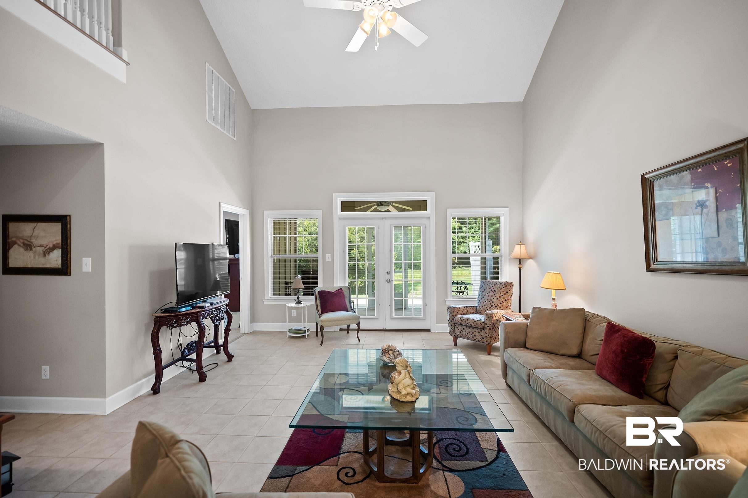 430 West Fort Morgan Road, Unit 704 Gulf Shores, AL 36542 - Photo 3 of 35 Spacious living area featuring vaulted ceilings, light-toned tile flooring, and multiple windows with exterior access