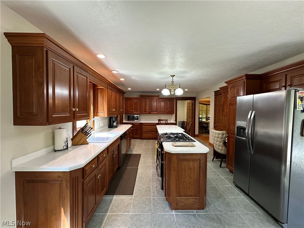 5233 Secrest Road Wooster, OH 44691 - Photo 24 of 33 Kitchen with stainless steel appliances, sink, pendant lighting, a kitchen island, and a chandelier