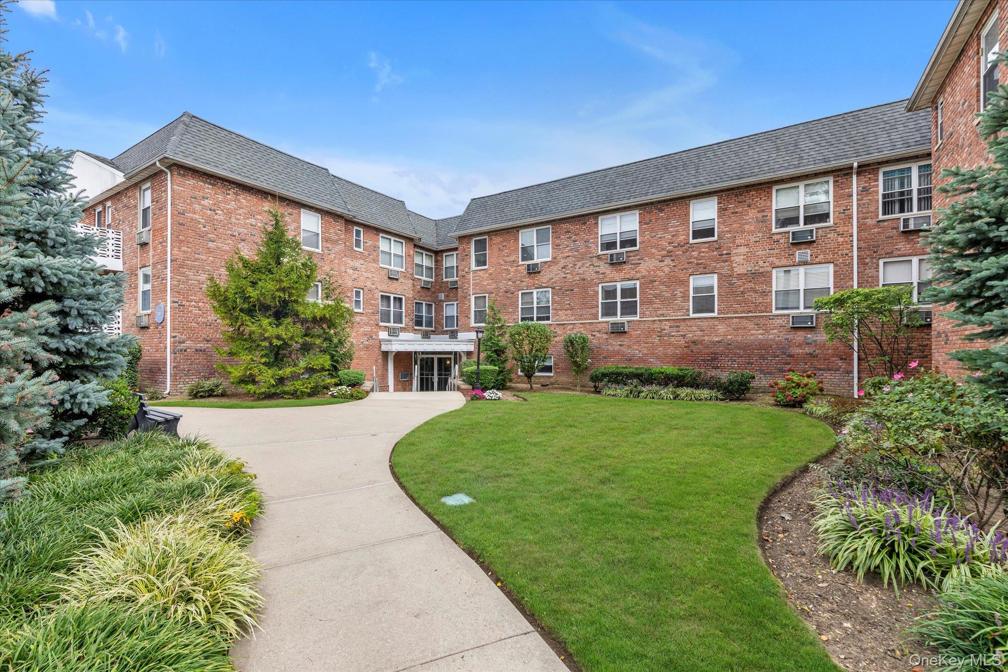 2 Fowler Avenue, Unit 228 Lynbrook, NY 11563 - Photo 1 of 18 a front view of a house with a yard and potted plants