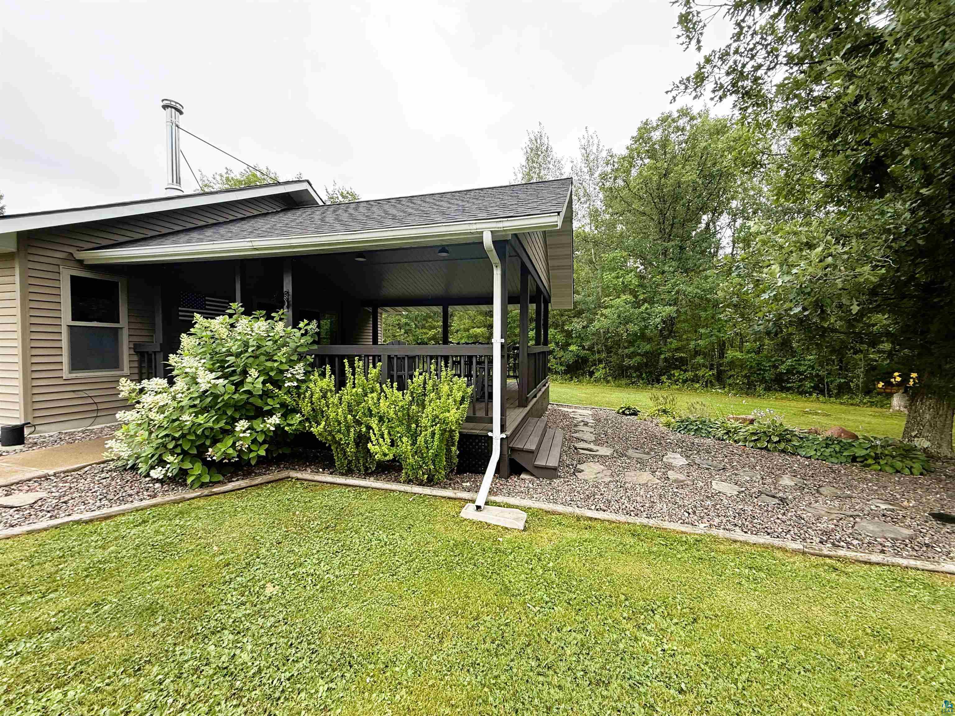 Covered porch with dark wood-finish railing, composite siding, and a gabled roofline