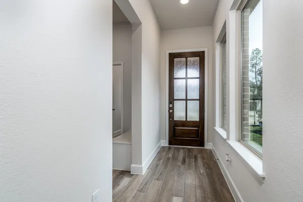 a view of an empty room with wooden floor and windows