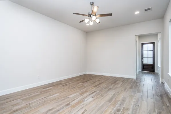 an empty room with wooden floor and windows
