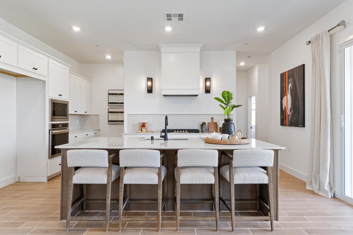 856 Traverse Drive Madera, CA 93636 - Photo 17 of 34 a white kitchen with a dining table chairs stainless steel appliances and cabinets