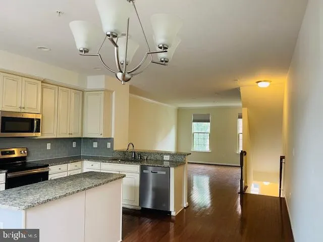 a kitchen with stainless steel appliances a sink a stove a refrigerator cabinets and a counter space