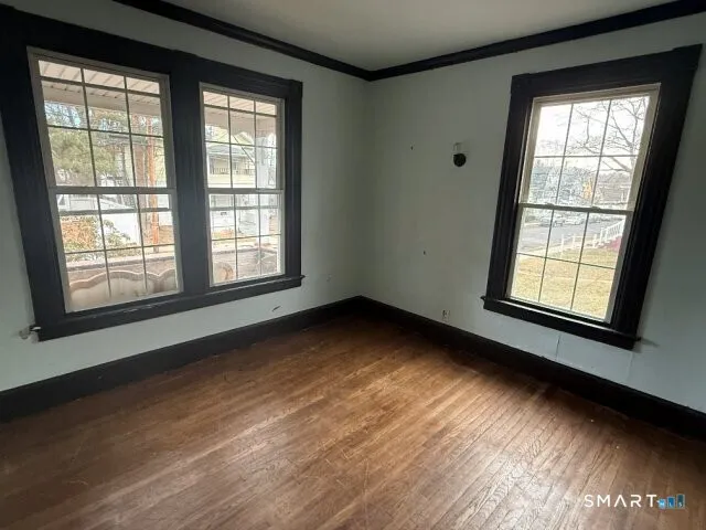 a view of an empty room with wooden floor and a window