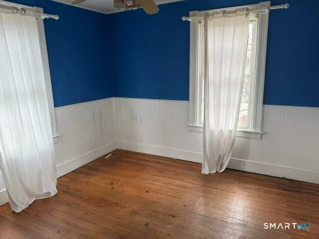 an empty room with wooden floor and windows with curtains