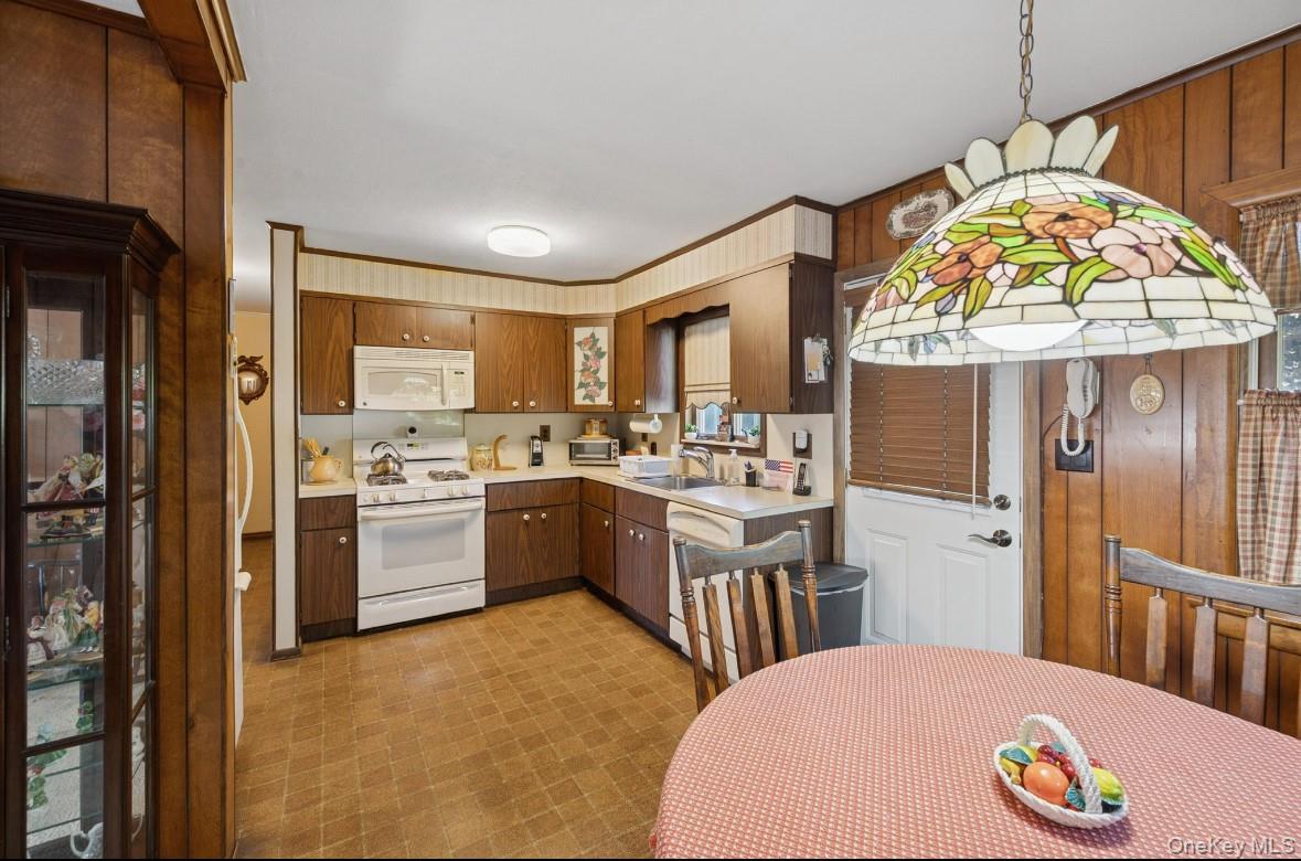 43 Briarcliff Road Westbury, NY 11590 - Photo 8 of 15 a kitchen with a refrigerator a stove a sink and a dining table with wooden floor