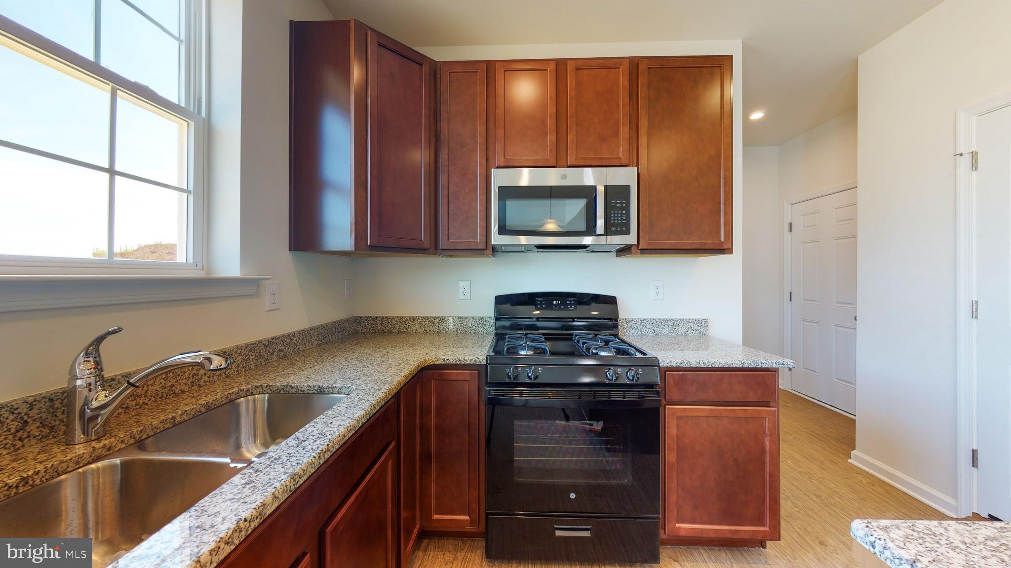211 Laks Court, Unit CHARLESTON Smyrna, DE 19977 - Photo 8 of 24 a kitchen with stainless steel appliances granite countertop a sink stove and microwave