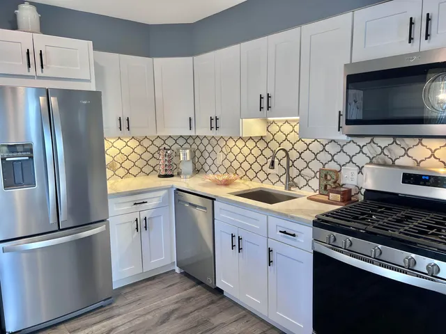 a kitchen with granite countertop white cabinets and stainless steel appliances