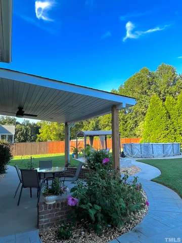 a view of a patio with table and chairs under an umbrella with a small yard