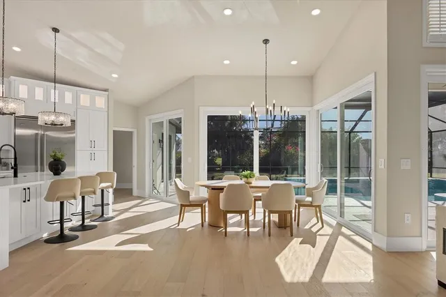 a kitchen with stainless steel appliances kitchen island granite countertop a refrigerator a stove and white cabinets with wooden floor