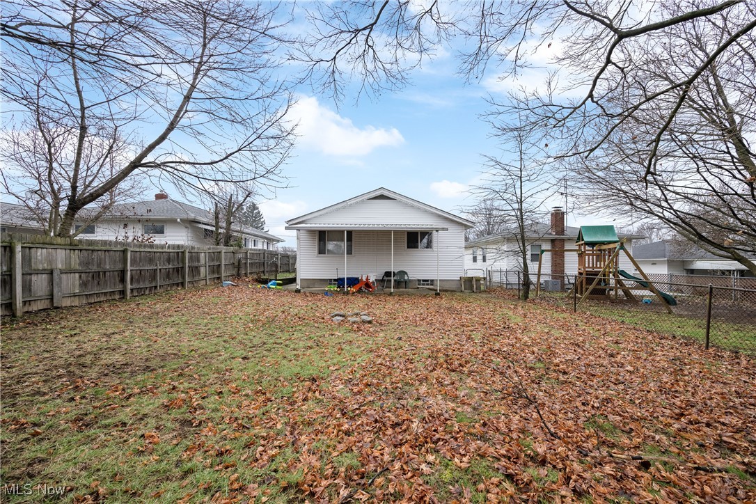 Rear view of property with a fenced backyard and a playground