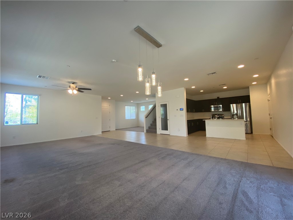 436 Cadence View Way Henderson, NV 89011 - Photo 35 of 36 An open floorplan seamlessly connects the living space to a modern kitchen, featuring recessed lighting and durable tile flooring.
