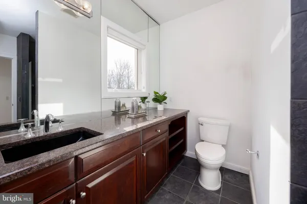 a bathroom with a granite countertop toilet sink and mirror