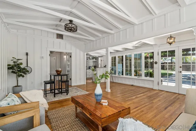 a living room with furniture large window and wooden floor