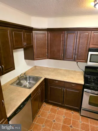 a kitchen with granite countertop a sink stove and refrigerator