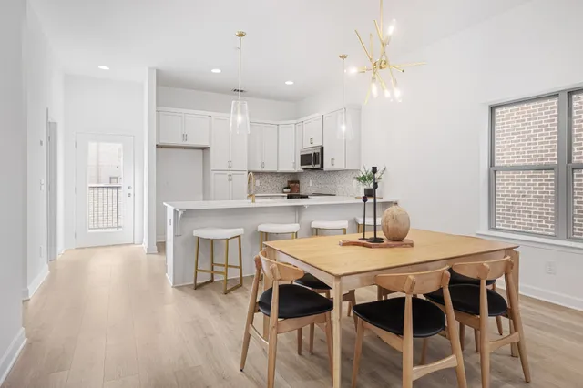 a kitchen with a dining table chairs wooden floor cabinets and appliances