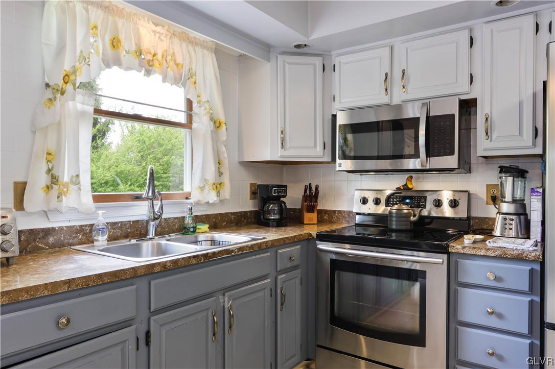 921 Point Phillips Road Bath, PA 18014 - Photo 6 of 29 a kitchen with granite countertop white cabinets a sink and a stove with wooden floor