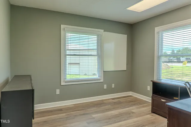 a view of an empty room with a window and wooden floor