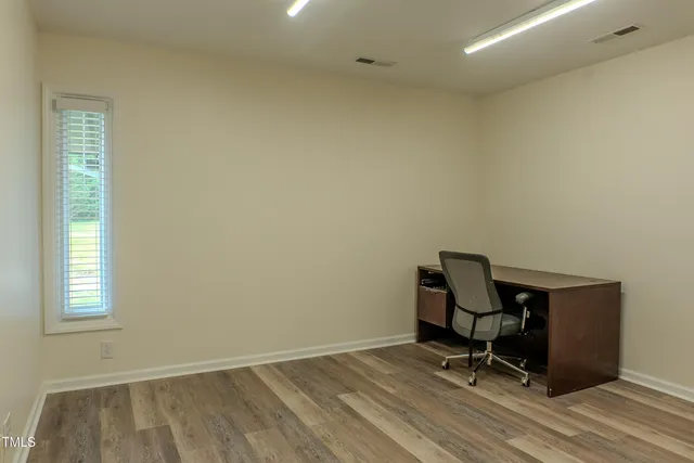 a view of a workspace with wooden floor and a window