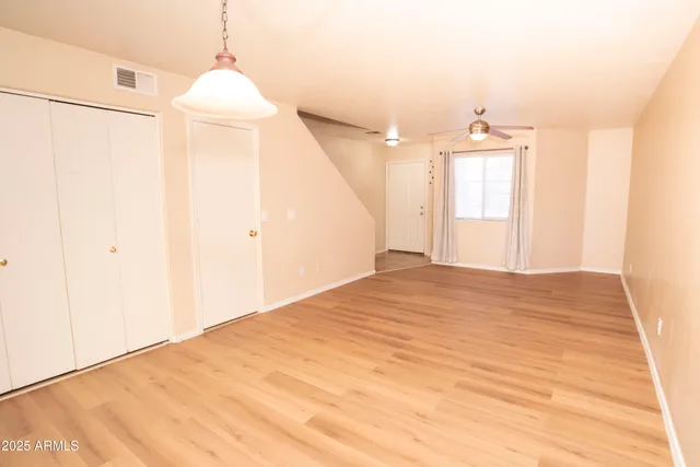 a view of empty room with wooden floor and fan