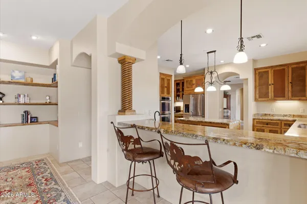 a room with stainless steel appliances kitchen island granite countertop a table chairs and a refrigerator