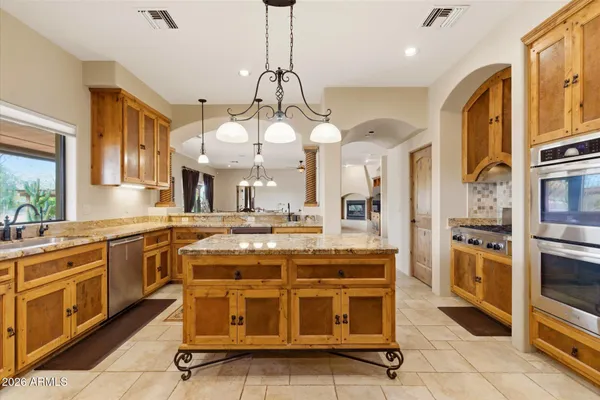 a kitchen with stainless steel appliances granite countertop a stove a sink a oven a dining table and chairs with wooden floor