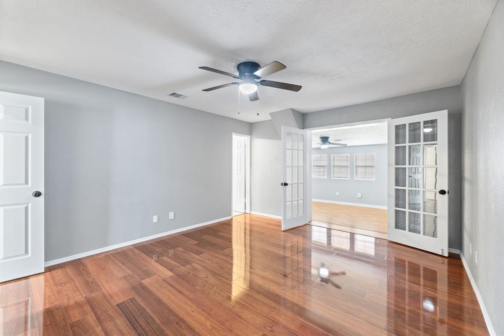 100 West Way Drive Allen, TX 75002 - Photo 13 of 31 Primary bedroom, ensuite bath, french doors open to private office or sitting area. Featuring wood finished floors, a textured ceiling, and a ceiling fan & closet.