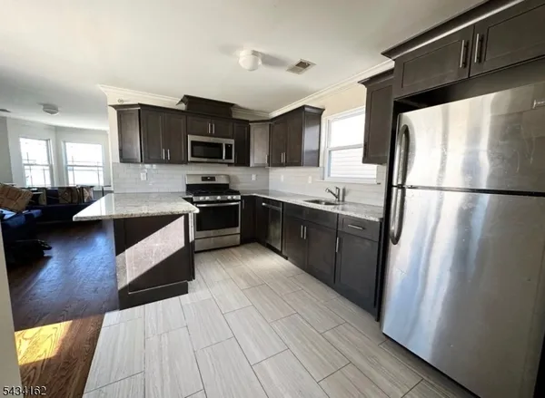 a kitchen with stainless steel appliances granite countertop a refrigerator a stove a sink and a microwave