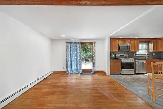 a view of a kitchen with stainless steel appliances wooden floor and chair