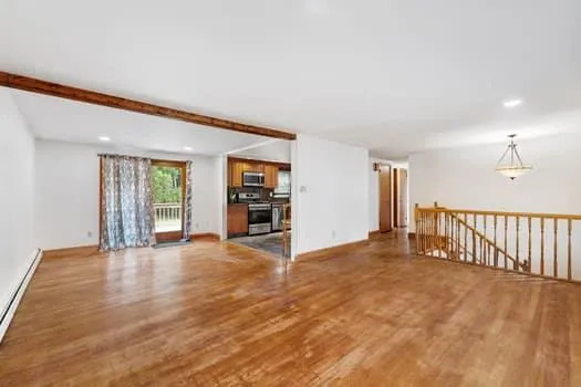 a view of an empty room with wooden floor and a window