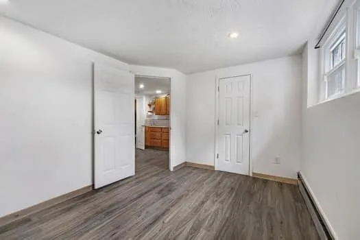 a view of an empty room with wooden floor and closet