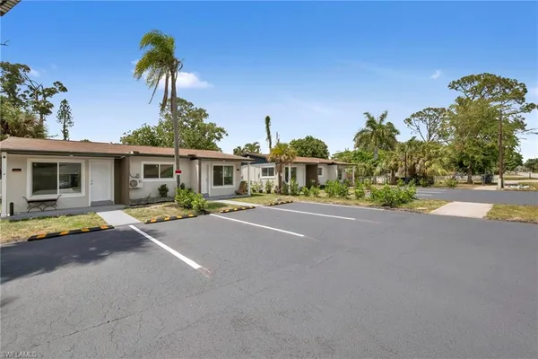 front view of a house with a yard and palm trees