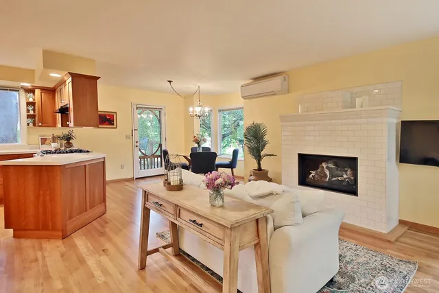 a living room with stainless steel appliances furniture a fireplace and a table