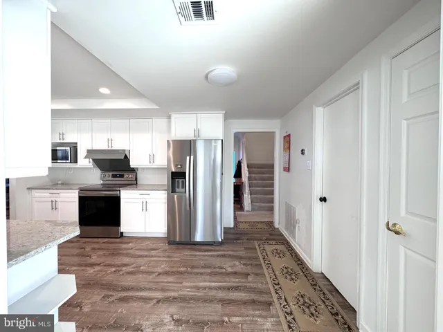 a kitchen with stainless steel appliances kitchen island granite countertop a refrigerator and a sink