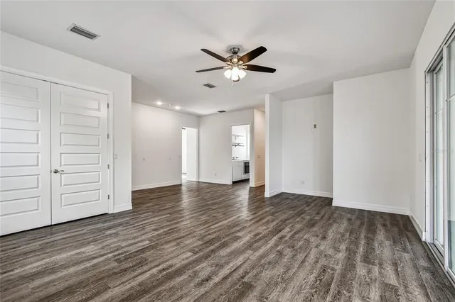 a view of empty room with wooden floor and fan