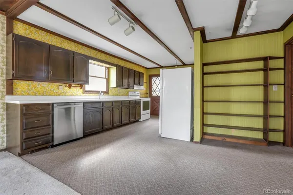 a view of a kitchen with stainless steel appliances wooden floor and staircase