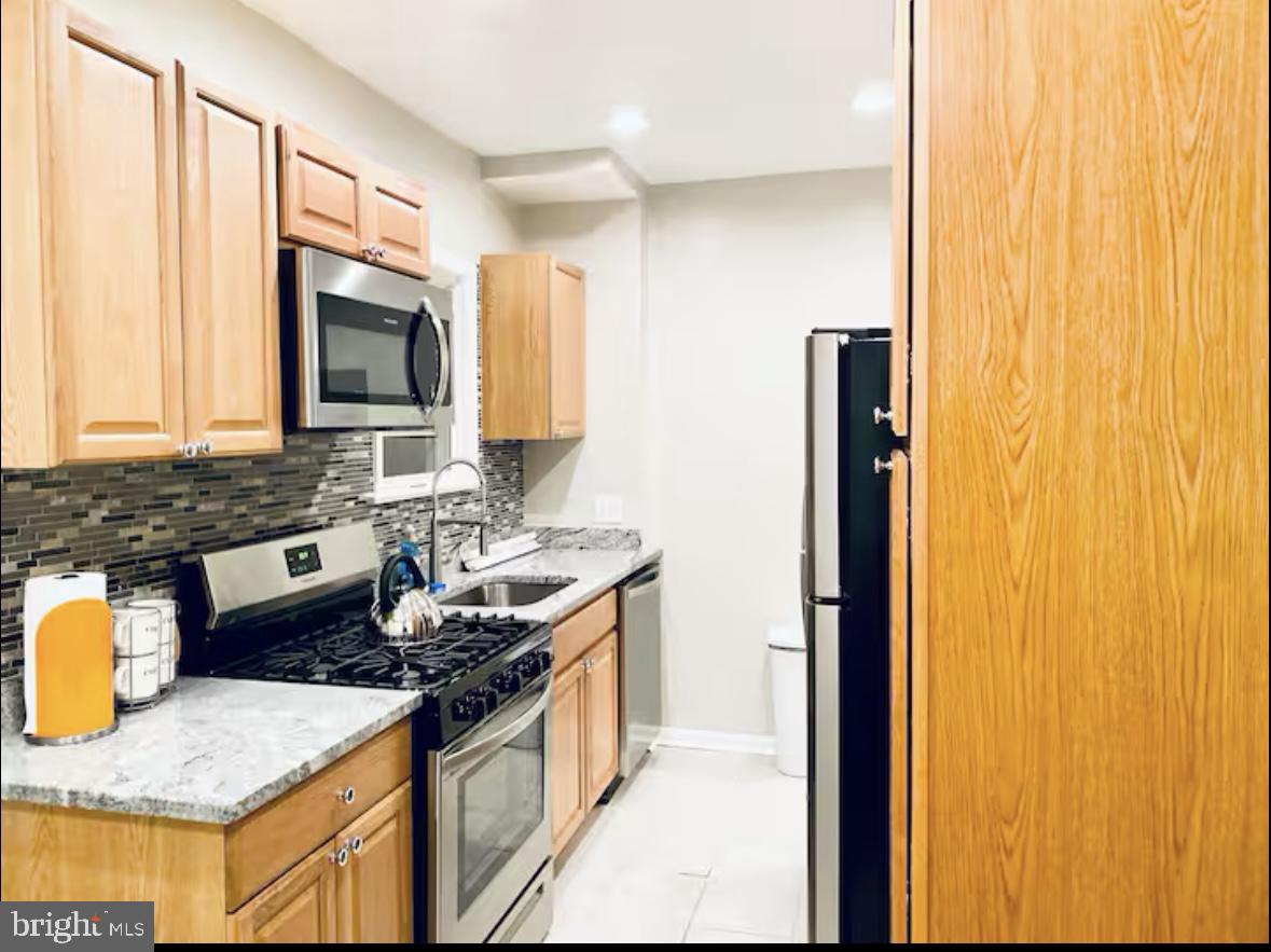 1268 Raum Street Northeast Washington, DC 20002 - Photo 19 of 46 a kitchen with stainless steel appliances granite countertop a stove a sink and a microwave