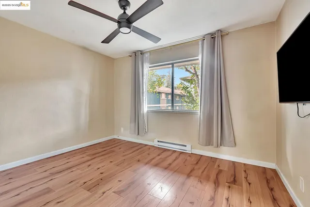 a view of empty room with wooden floor and fan