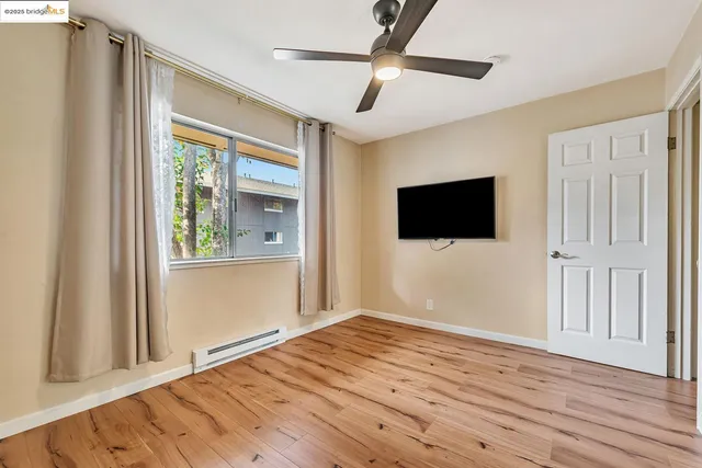 a view of empty room with wooden floor and fan