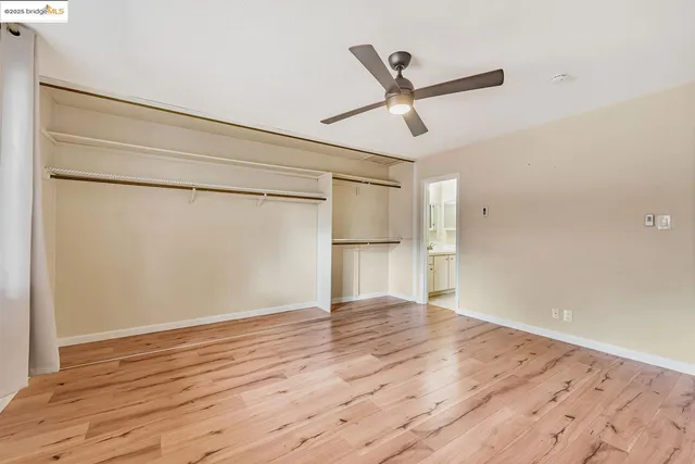 a view of empty room with wooden floor and ceiling fan