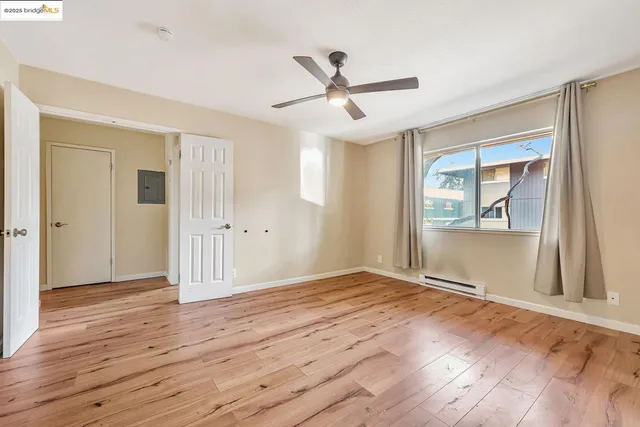 a view of an empty room with wooden floor and a window