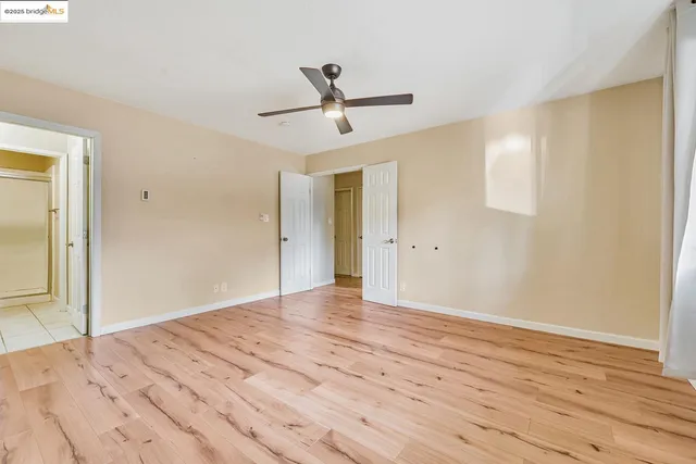 a view of empty room with wooden floor and fan