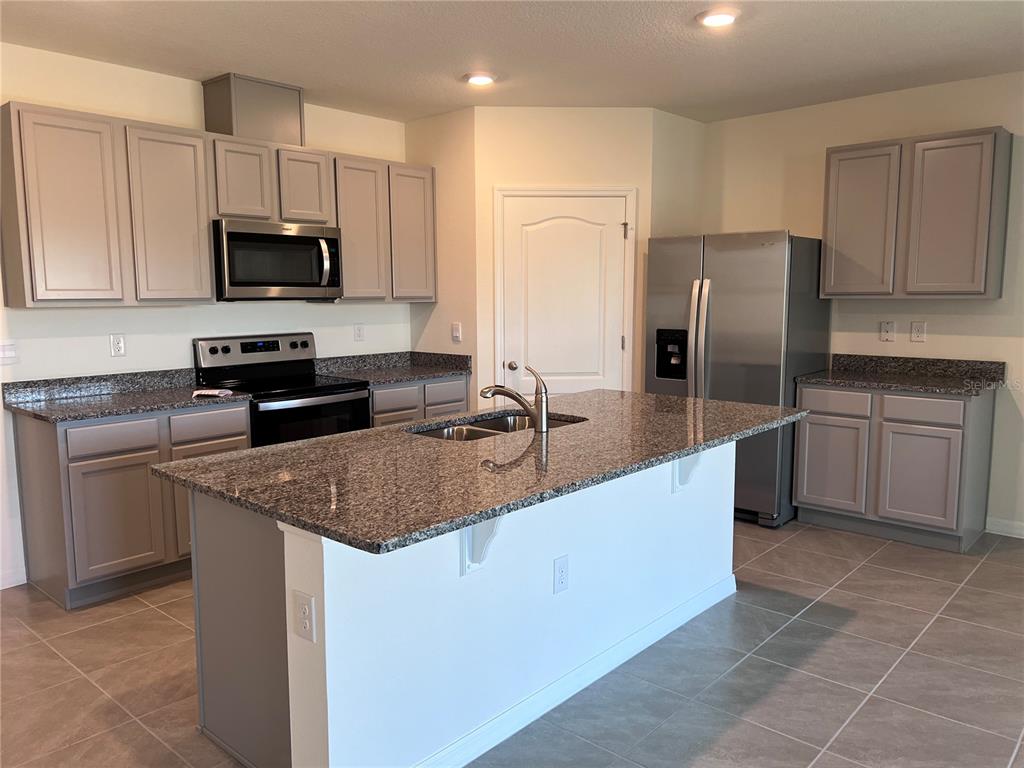 2738 Swooping Sparrow Drive Harmony, FL 34773 - Photo 2 of 9 a kitchen with stainless steel appliances granite countertop a sink a stove a refrigerator and a microwave